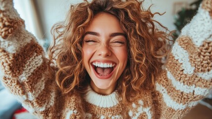 A woman with curly hair, her face full of happiness, throws her arms up in an expression of pure joy and excitement in an indoor setting.