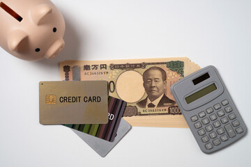 クレジットカードと一万円札と電卓と貯金箱
