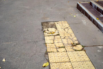 yellow anti-slip tile, fragmented on the pavement, symbolizing disruption and the fragility of...