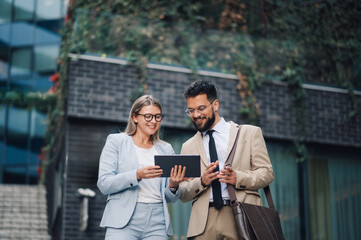 Business people using digital tablet outdoors discussing work