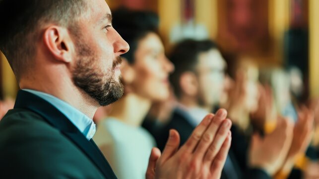 Man in suit clapping in audience at event.