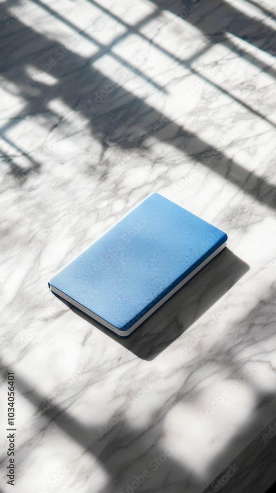 Poster minimalist blue notebook on marble surface with dramatic window shadow patterns, symbolizing creativ