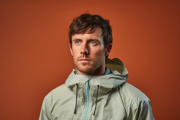 Fototapeta premium Portrait of a merry man in his 30s wearing a lightweight packable anorak over pastel or soft colors background