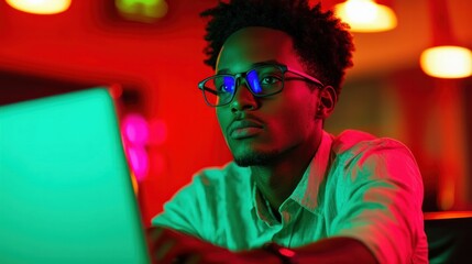 Focused individual engaged in deep work on laptop in vibrant ambient lighting highlighting concentration and modern technology use