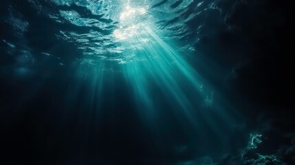Fototapeta premium Sunbeams shine through the water surface, illuminating the dark blue depths of the ocean.