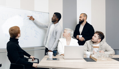 Diverse team engaged in modern office environment discussing business strategy at whiteboard. atmosphere is collaborative and inclusive, featuring professionals of varying backgrounds and ethnicities.