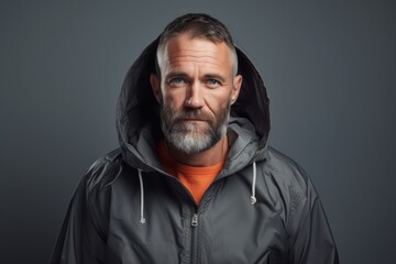 Fototapeta premium Portrait of a glad man in his 40s wearing a functional windbreaker over minimalist or empty room background