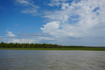 A serene landscape featuring a river and clouds above a tranquil lake nestled in a lush forest