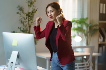 Young asian businesswoman is cheering in her home office while working on a desktop computer