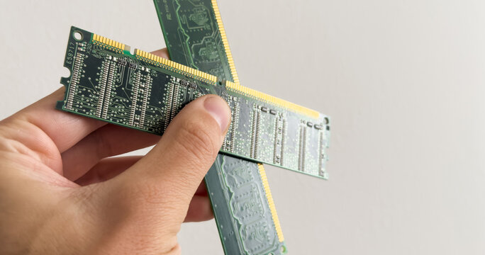 Man holding up a RAM module, or random access memory, in which all storage locations can be rapidly accessed in the same amount of time used by a computer operating system, on white