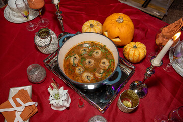 A spooky stew made up of dumplings with olives to male it look like eye balls for Halloween placed as part of a Halloween scary party food decorations