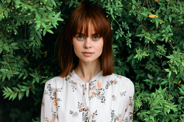 Serene redhead woman surrounded by lush greenery gazes off into the distance