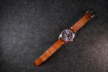 Wristwatch with leather strap. Mechanical watch. Brown strap. Purple dial. Men's accessory. Dark background. Product shot