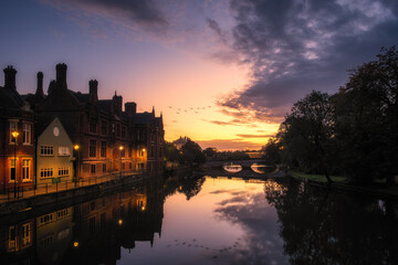 Obraz premium Buildings reflected in the still waters of the River Great Ouse at sunrise in Bedford, England with the Town Bridge in the distance