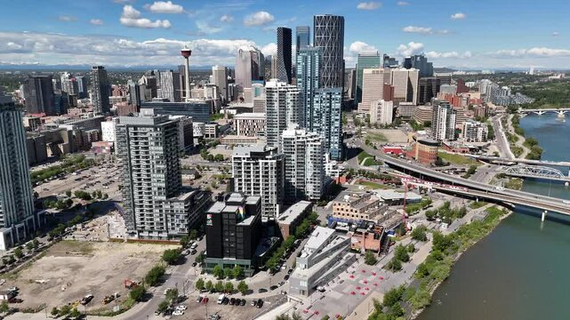 Calgary Alberta Canada, June 25 2024: Orbital aerial downtown skyline rotating shot overlooking transit train crossing bridge with popular attractions.
