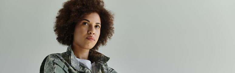 A determined young African American woman embodies strength while wearing a camouflage uniform.