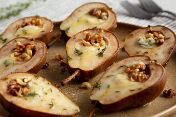 Homemade Blue Cheese Stuffed Pears with Honey, Thyme and Walnuts on a Plate, side view. Close-up.