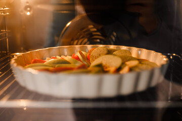 An apple pie in a white dish is baking inside the oven