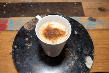 A Pumpkin Spice Latte in a white cup on a wooden kitchen table or worktop