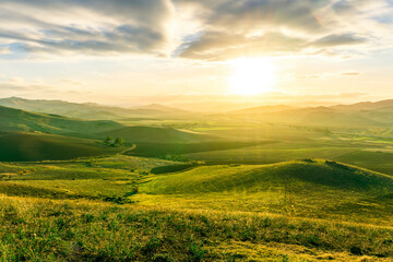 spring green field landscape in beautiful countryside with green and yellow grass, rural hills and amazing cloudy sky on background. Agriculture landscape with rural view