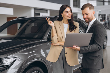 Male car salesman, recommends a car to a woman buyer, inspects cars in the showroom, the seller...