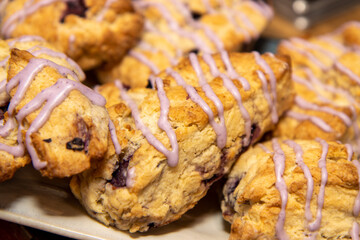 A delicious plate of pumpkin spice scones covered in pink icing on a kitchen work top