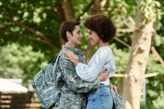 A young soldier in camouflage is joyfully welcomed home by her wife in a heartfelt moment. - Powered by Adobe