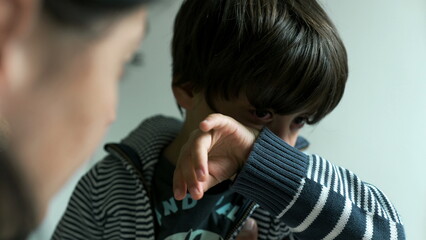 Mother talking while her son listens, visibly upset and emotional, with tears in his eyes. The mother offers comfort and guidance in a supportive home environment