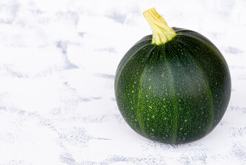 organic round green courgettes zucchini on gray rustic background.