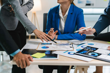 Team of business professionals is gathered around a desk, collaborating on analyzing financial data...