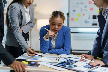 Fototapeta premium Team of business professionals are discussing over financial data on digital tablet and paperwork with charts and graphs