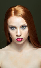 Fototapeta premium Woman with red hair and red lipstick poses for a photo. She has thick, beautiful hair. Fashion and beauty concept.