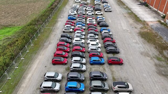 drone revealing New cars parked in rows at distribution center parking lot