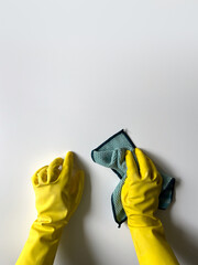 Hands in a yellow rubber gloves for cleaning and household chores holding a green cleaning cloth. Hands in protective gloves on a white background with a place for text.