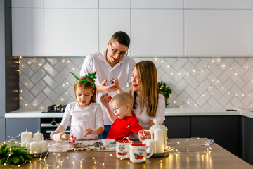 Happy family parents with two kids making xmas cookies at home during winter holidays.