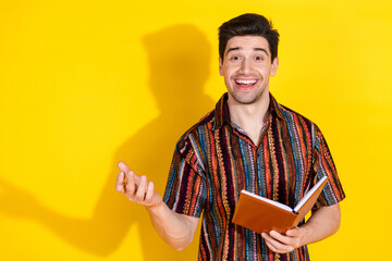 Portrait of nice young man talk hold book wear shirt isolated on yellow color background