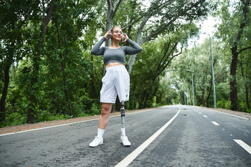 A young woman with a prosthetic leg embraces fitness while enjoying nature along a picturesque...