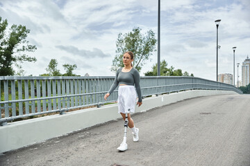 A young woman in sportswear confidently walks along a bridge, embracing her active lifestyle outdoors.