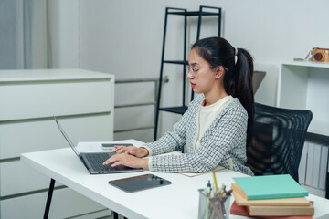 Asian woman sitting at desk, staring at laptop with a stressed expression. Surrounded by paperwork and office tools, she focuses on task at hand. Office environment, organized and modern workspace.