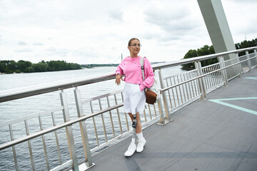 A determined young woman with a prosthetic leg is actively walking outdoors by the water.