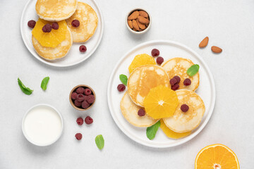 Pancakes with orange and raspberries in plate top view on white background with copy space. Morning traditional breakfast