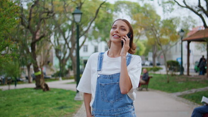 Carefree lady chatting smartphone walking city park closeup. Woman talking 