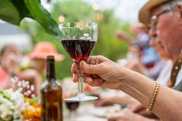 Close-up of red wine glass at outdoor senior gathering