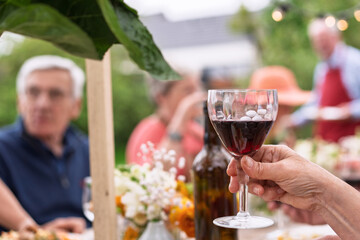 Close-up of red wine glass at outdoor senior gathering