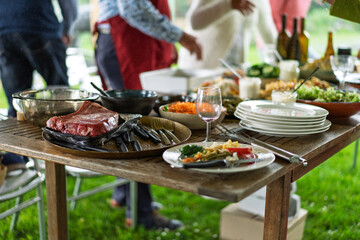 Outdoor barbecue party with steak and salads on rustic wooden table