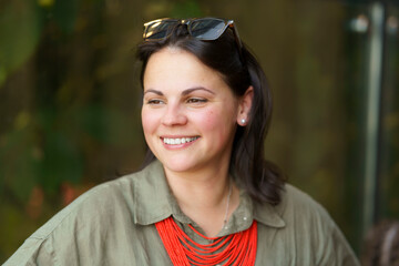 Beautiful dark-haired European woman in her thirties poses for a portrait photo in a khaki linen...