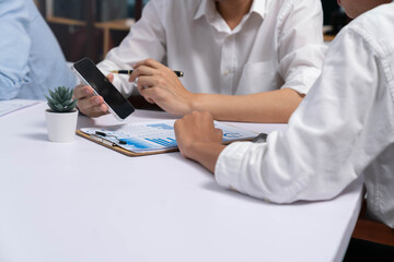 Fototapeta premium Diverse corporate audit team or company bookkeeper and accountant consultant calculate account expenses and income budget for tax refunds using blank screen smartphopne in busy workspace. Prudent