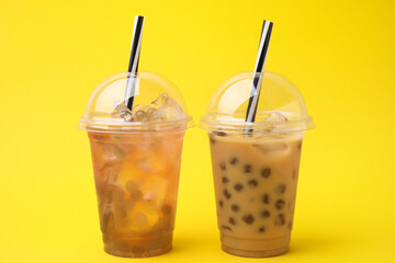 Tasty bubble tea in plastic cups on yellow background