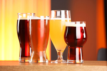 Glasses with different types of beer on wooden table indoors