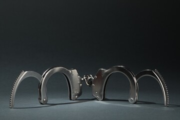 Metal chain handcuffs on grey background, closeup. Space for text